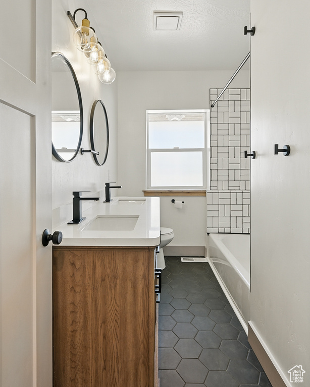Bathroom featuring double vanity, tile patterned flooring, and washtub / shower combination