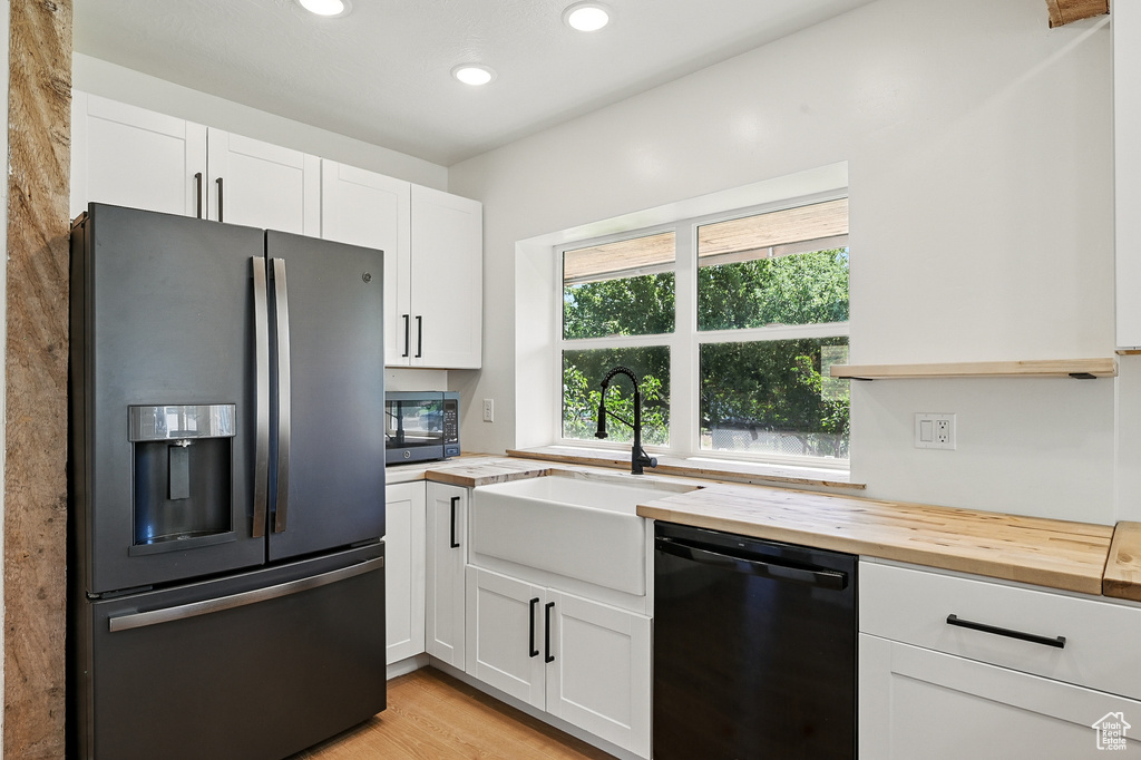 Kitchen featuring black appliances, butcher block countertops, white cabinets, and recessed lighting
