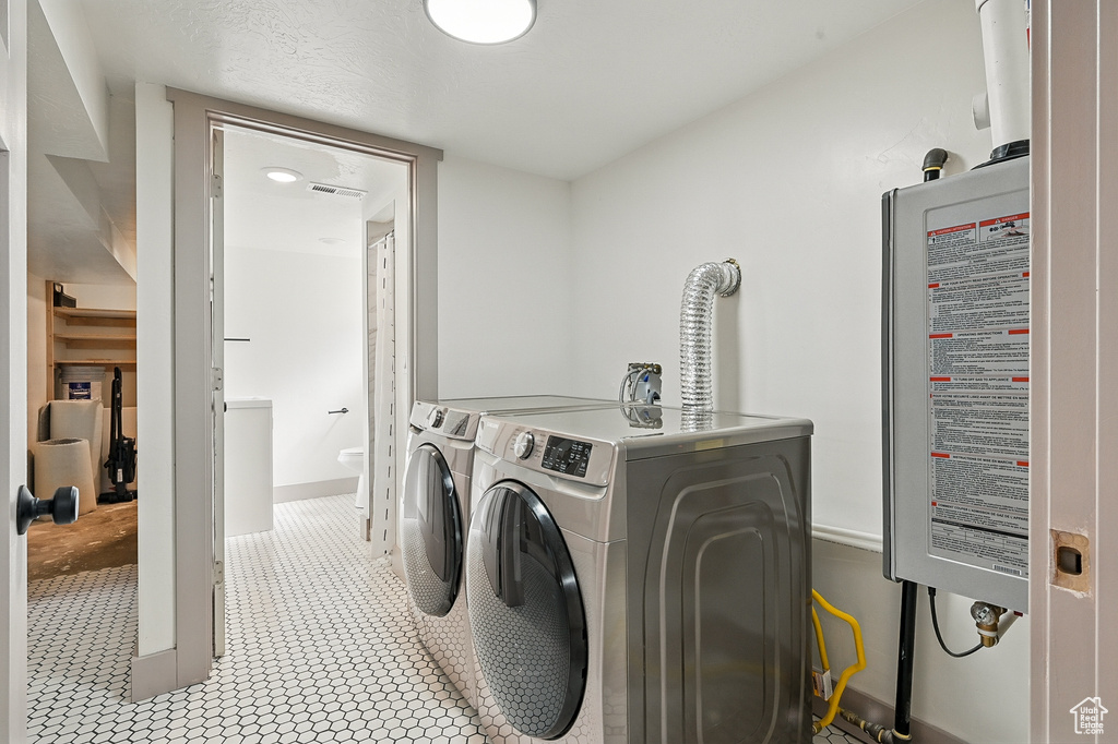 Laundry room featuring washer and clothes dryer and tankless water heater
