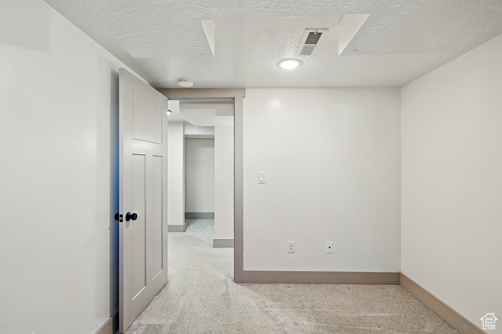 Empty room with light colored carpet and a textured ceiling