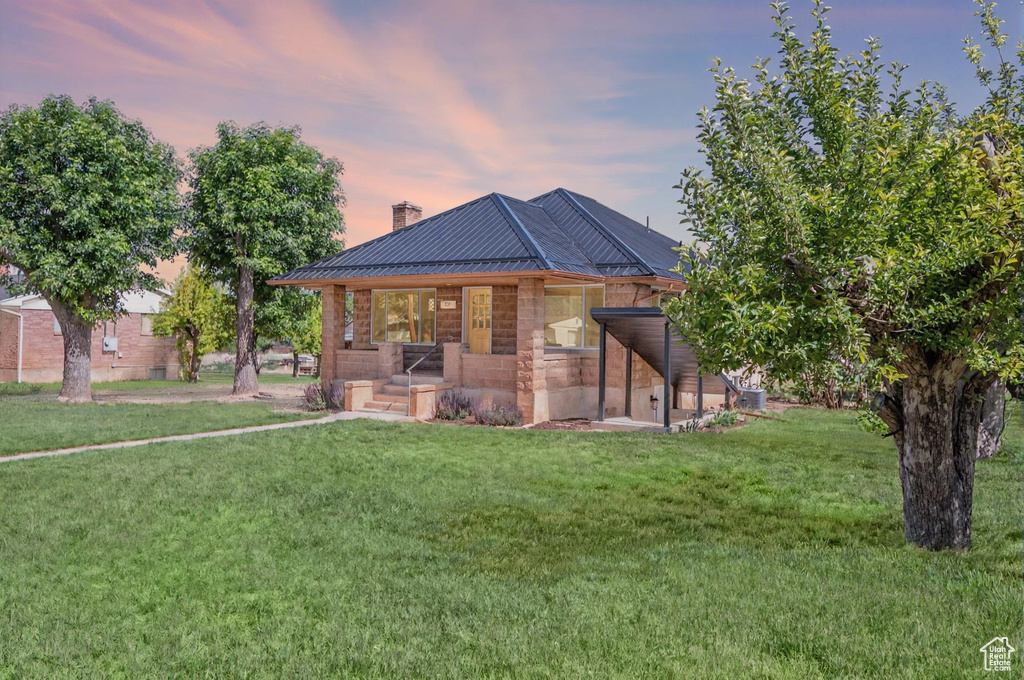 Rear view of property featuring covered porch, a chimney, and a yard
