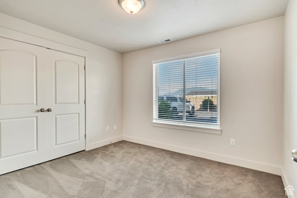 Unfurnished bedroom featuring light colored carpet and a closet
