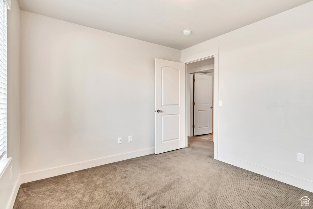 Empty room featuring light carpet and a smoke detector