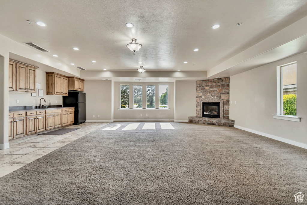 Unfurnished living room featuring recessed lighting, plenty of natural light, light carpet, a fireplace, and a textured ceiling