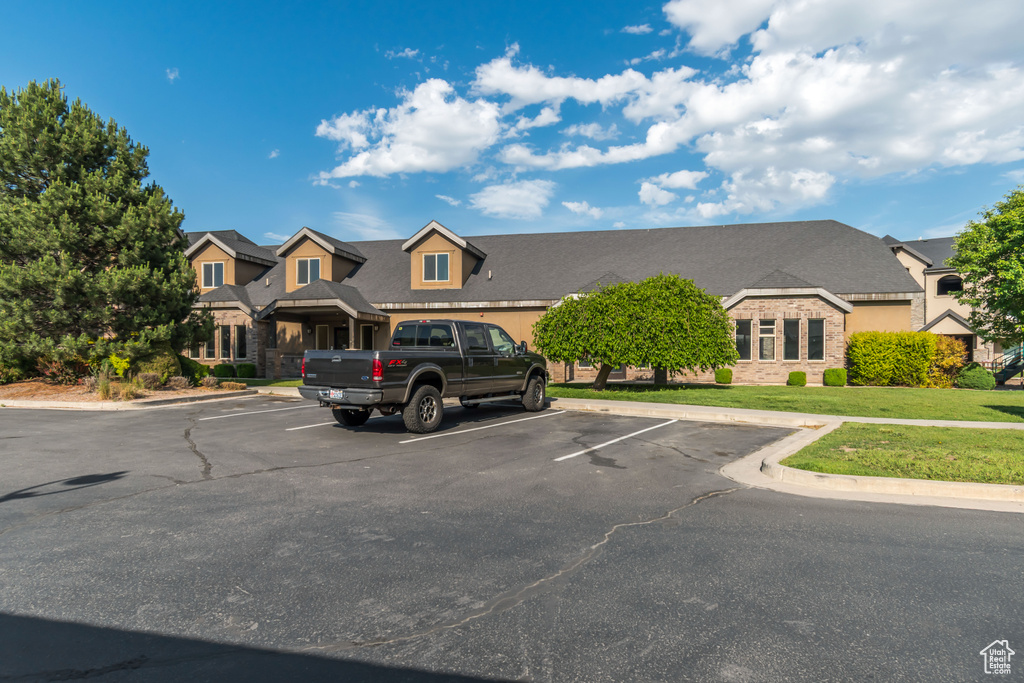View of front of property with uncovered parking, a front yard, and stone siding