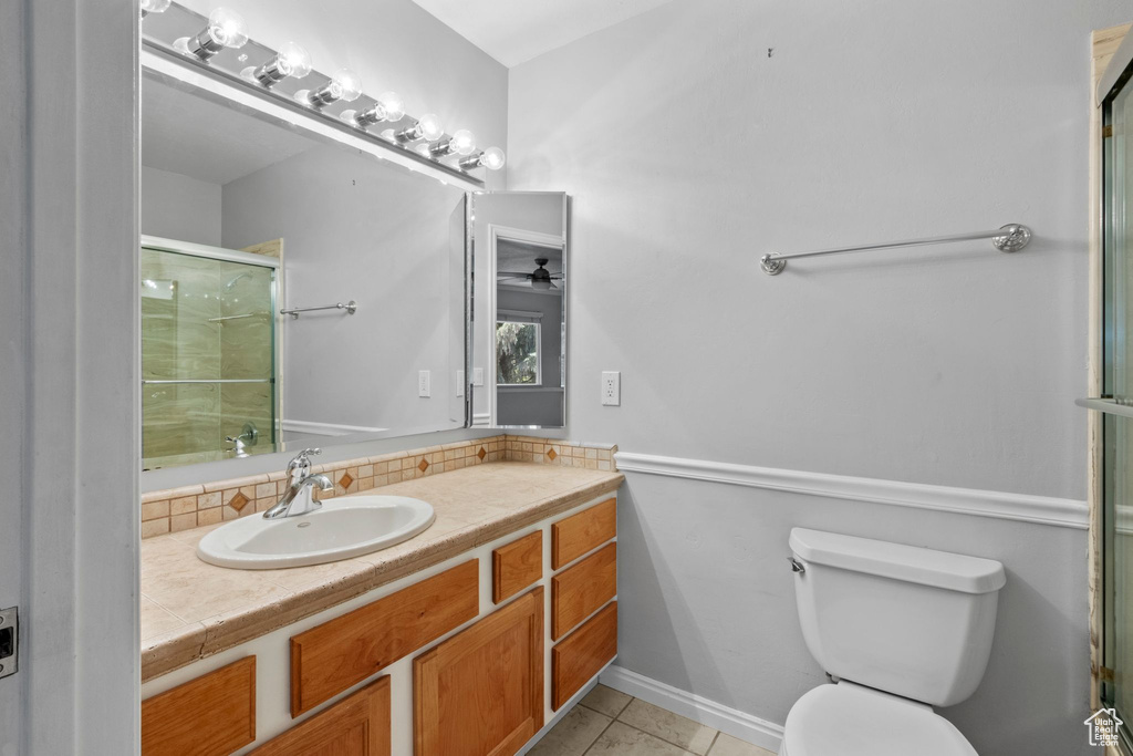 Full bathroom with a shower with shower door, vanity, tile patterned floors, ceiling fan, and backsplash