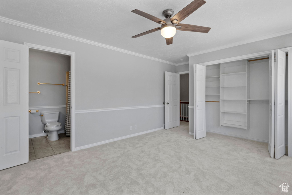 Unfurnished bedroom with carpet floors, ornamental molding, ensuite bathroom, ceiling fan, and a closet
