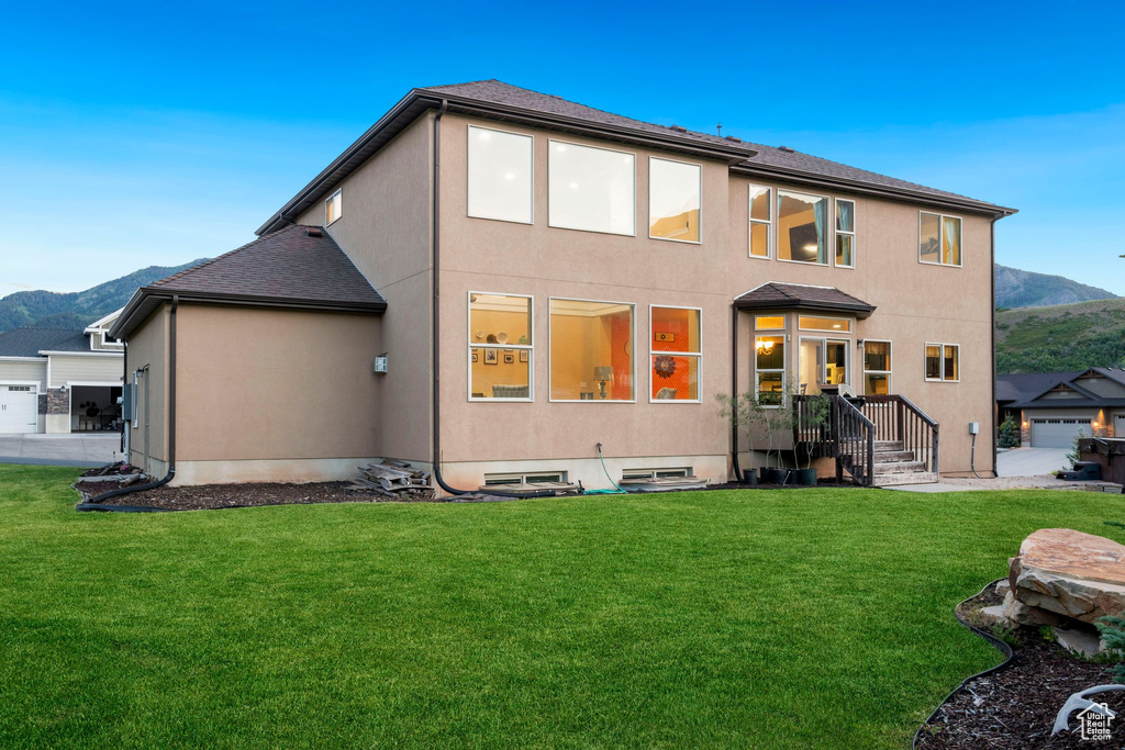 Rear view of house with a mountain view, a yard, and stucco siding
