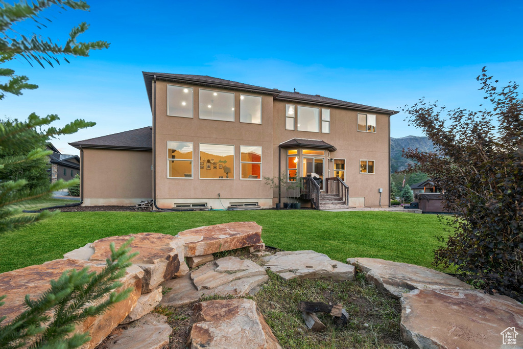 Rear view of house featuring a lawn and stucco siding