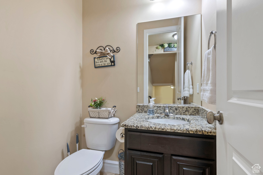 Bathroom with toilet, vanity, and baseboards