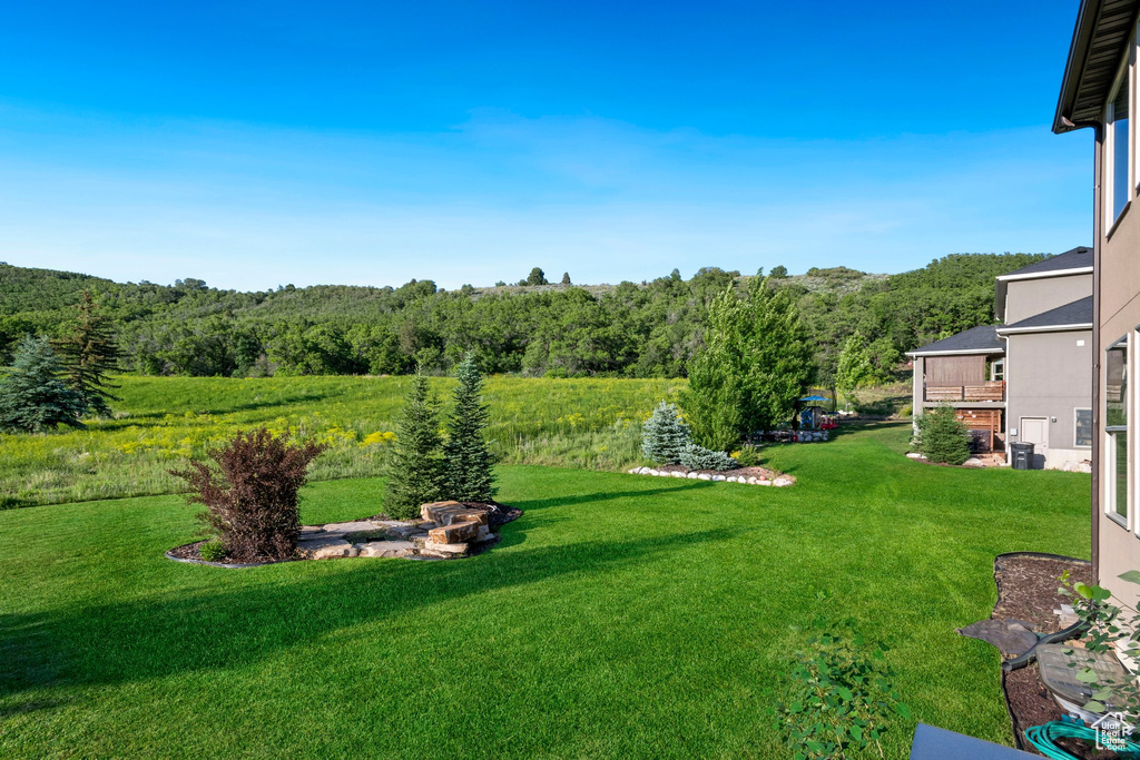 View of grassy yard featuring a wooded view