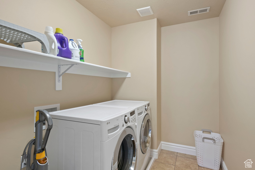 Washroom with separate washer and dryer, baseboards, and light tile patterned floors