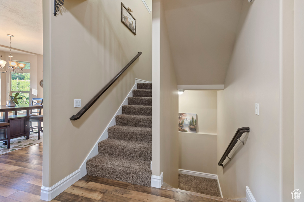 Stairway featuring wood finished floors, a chandelier, and baseboards