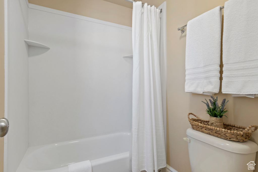 Full bathroom with toilet and shower / tub combo with curtain