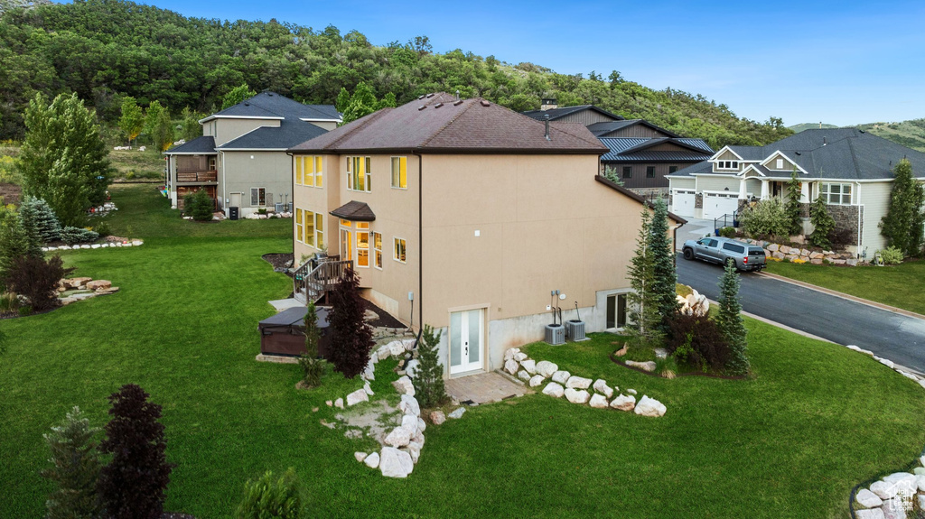 View of side of home featuring french doors, a yard, stucco siding, asphalt driveway, and a residential view
