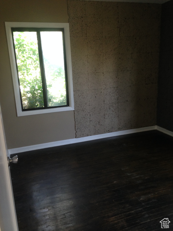 Spare room with dark wood-style flooring and baseboards