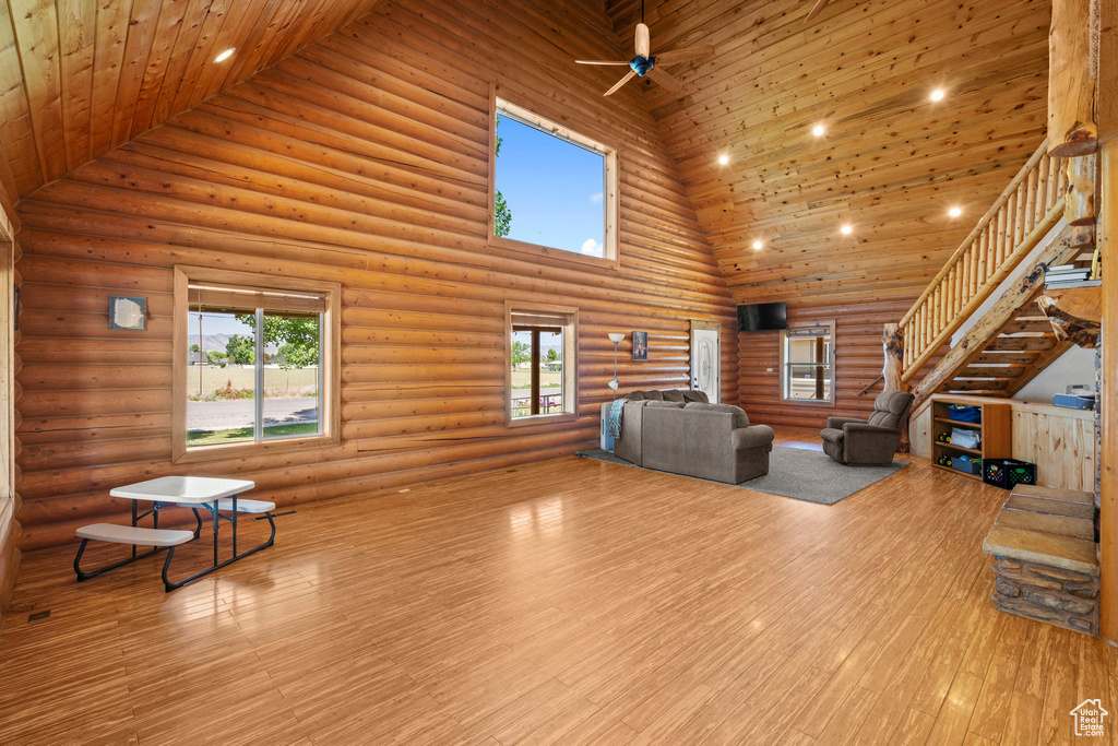 Living room featuring high vaulted ceiling, stairway, wood finished floors, log walls, and wood ceiling