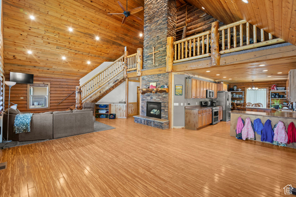 Living area with high vaulted ceiling, stairs, light wood finished floors, log walls, and wood ceiling
