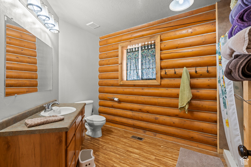 Bathroom featuring vanity, rustic walls, and wood finished floors