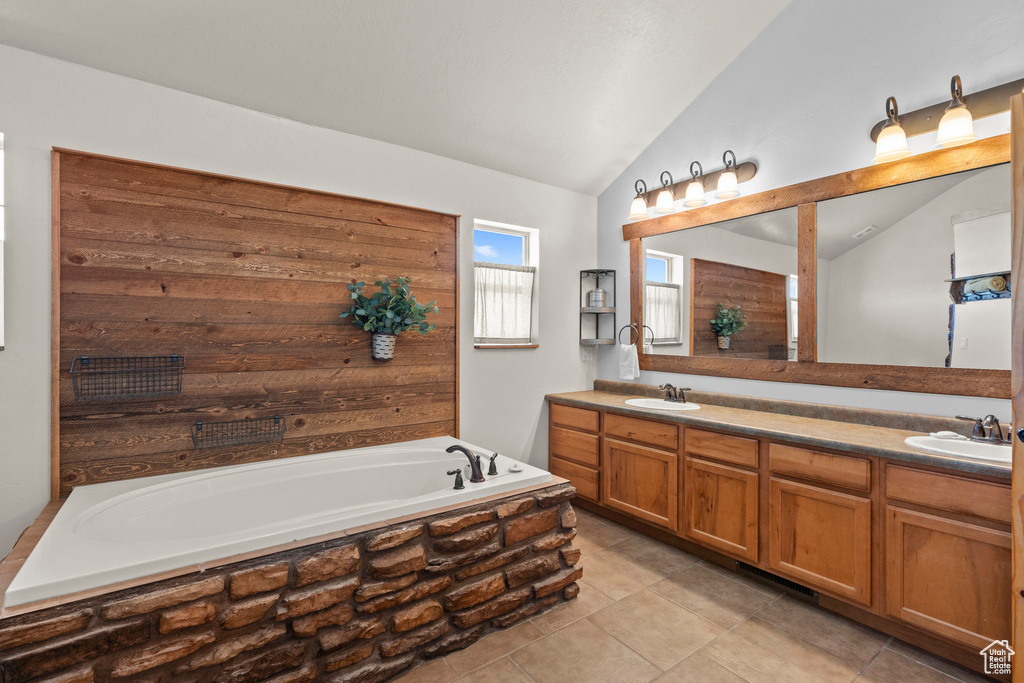 Full bathroom with lofted ceiling, double vanity, a garden tub, and tile patterned flooring