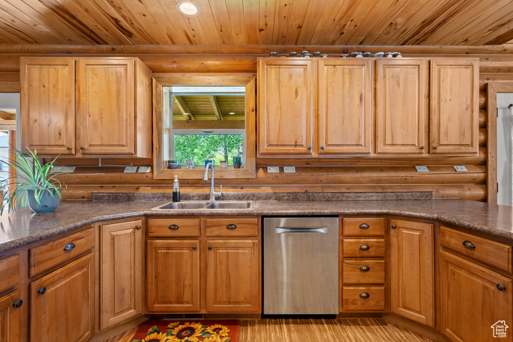 Kitchen with stainless steel dishwasher, rustic walls, wood ceiling, dark countertops, and light wood-style floors