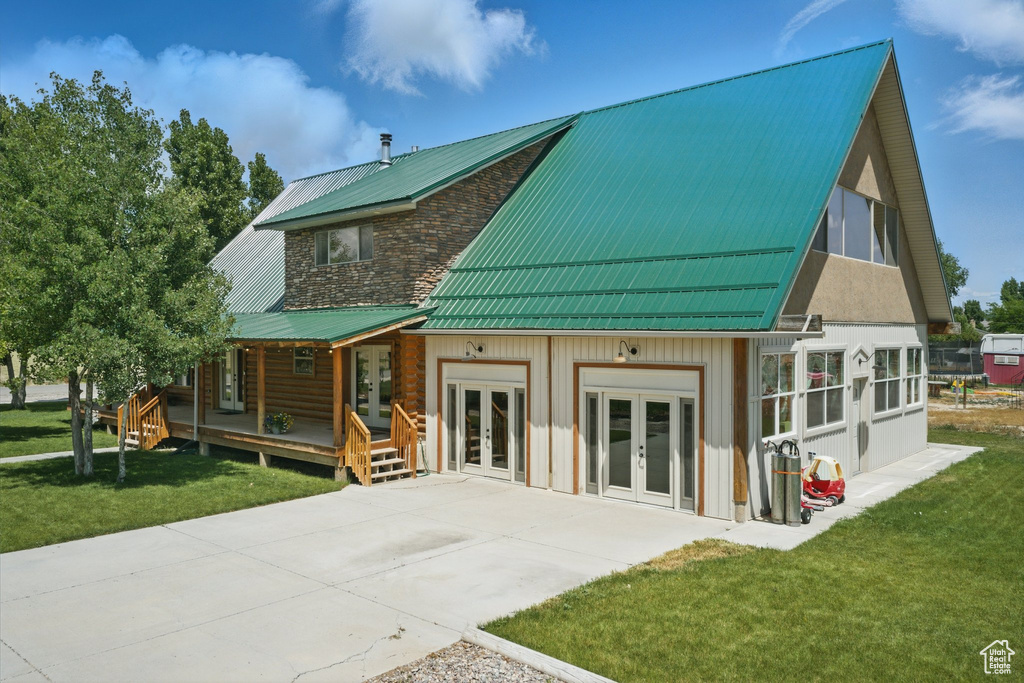 Back of property featuring french doors, a yard, and a metal roof