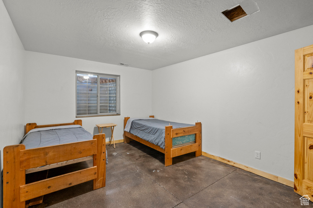Bedroom featuring concrete flooring and a textured ceiling