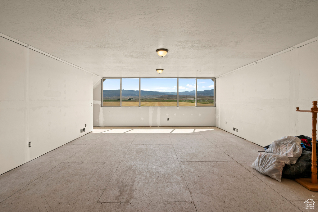 Empty room featuring a mountain view and a textured ceiling