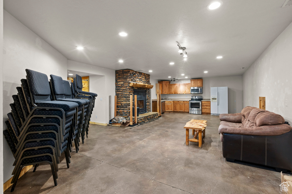 Living area with finished concrete floors, recessed lighting, and a stone fireplace