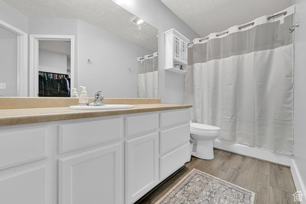 Full bath featuring vanity, wood finished floors, a textured ceiling, and shower / bath combination with curtain
