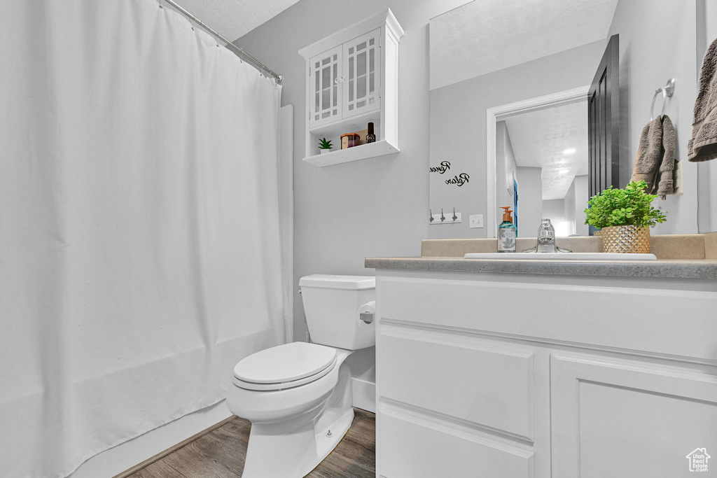 Bathroom featuring wood finished floors, vanity, and shower / bath combo with shower curtain