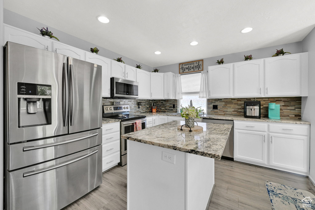 Kitchen with appliances with stainless steel finishes, white cabinetry, backsplash, a center island, and recessed lighting
