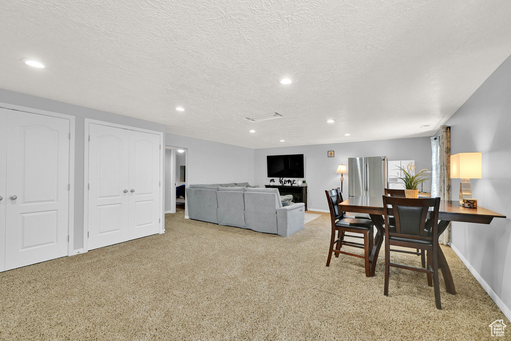 Carpeted dining room with recessed lighting and a textured ceiling
