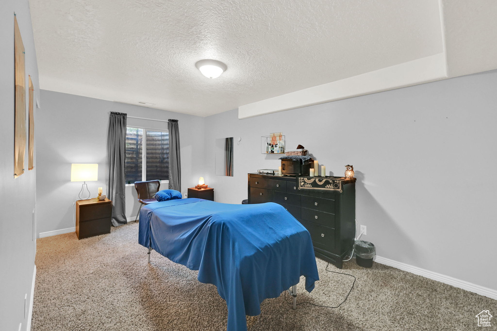 Carpeted bedroom featuring a textured ceiling and baseboards