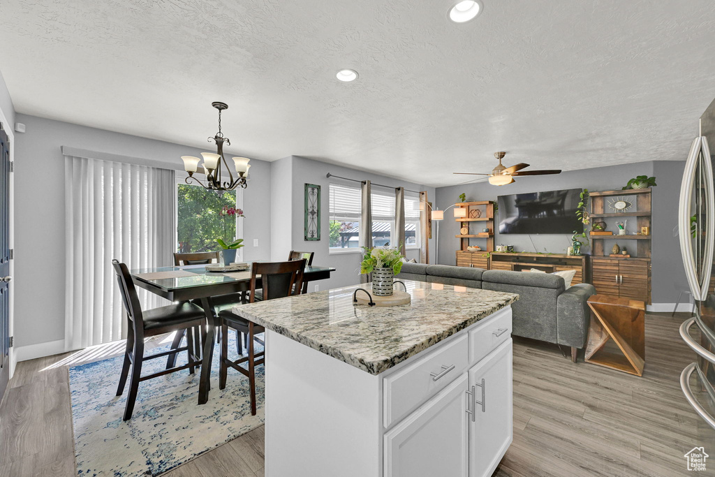 Kitchen with a textured ceiling, a chandelier, a ceiling fan, white cabinetry, and a kitchen island