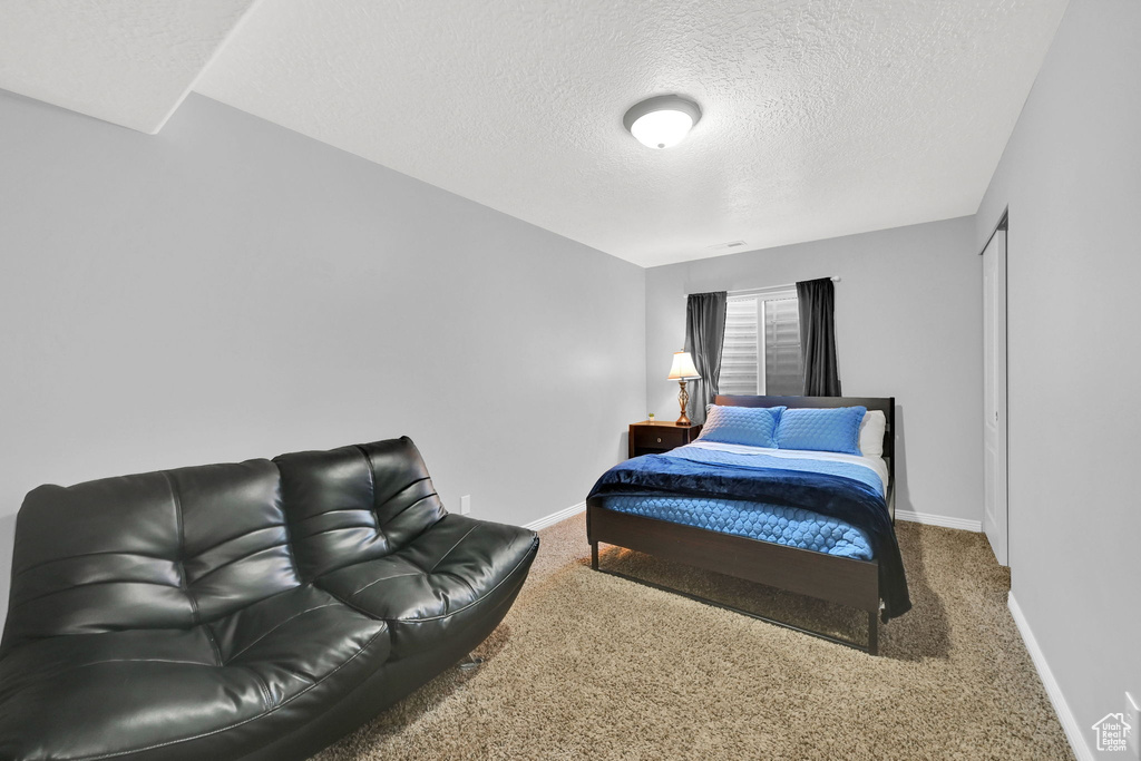 Carpeted bedroom featuring a textured ceiling and baseboards