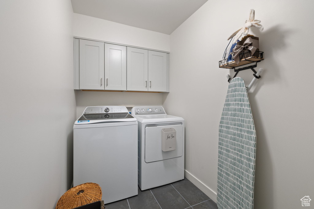 Laundry area with cabinet space, washer and clothes dryer, a heating unit, and dark tile patterned flooring