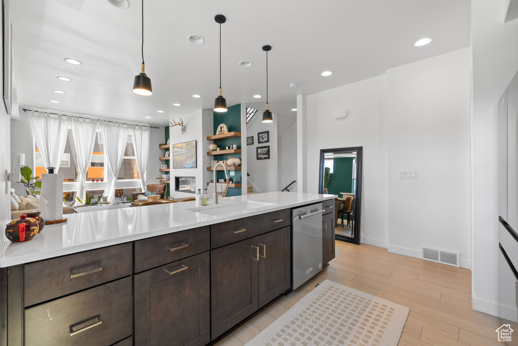 Kitchen with stainless steel dishwasher, dark brown cabinetry, light countertops, recessed lighting, and pendant lighting
