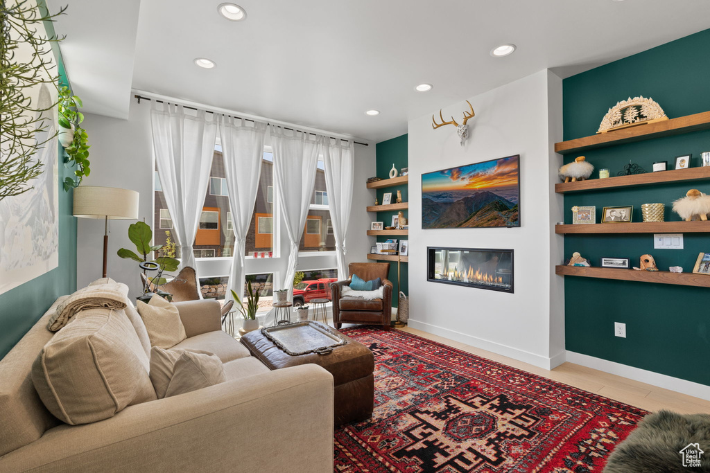 Living area with a glass covered fireplace, recessed lighting, and built in shelves