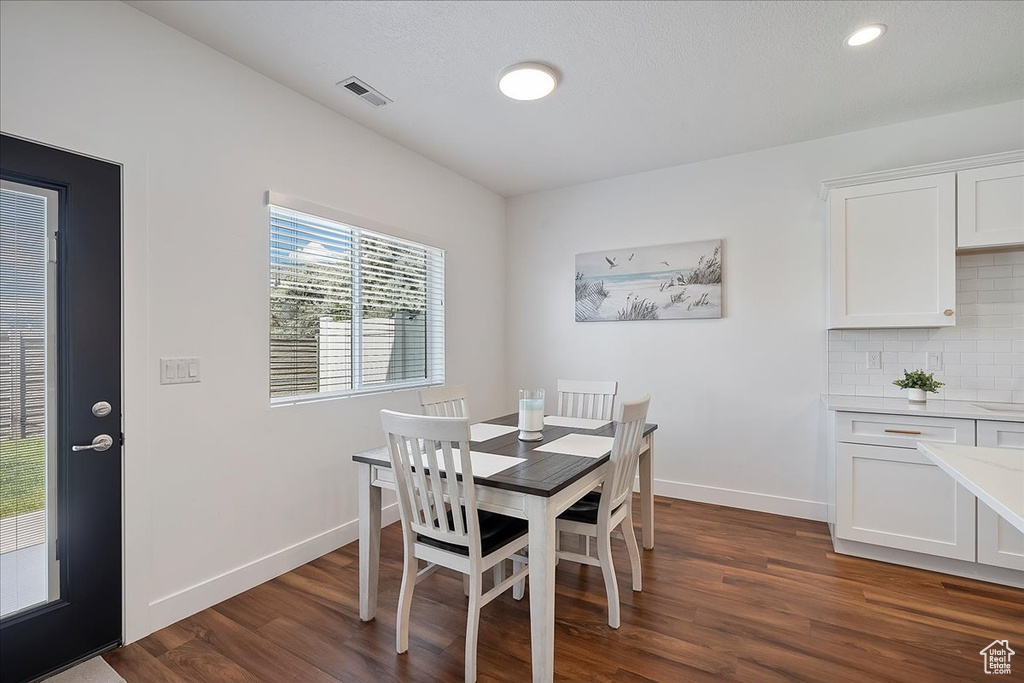 Dining room with dark wood-style flooring and recessed lighting