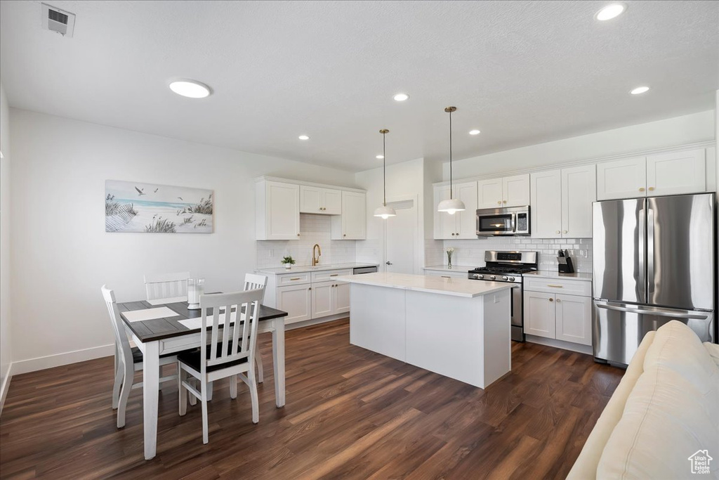 Kitchen with appliances with stainless steel finishes, decorative backsplash, a center island, white cabinets, and light countertops