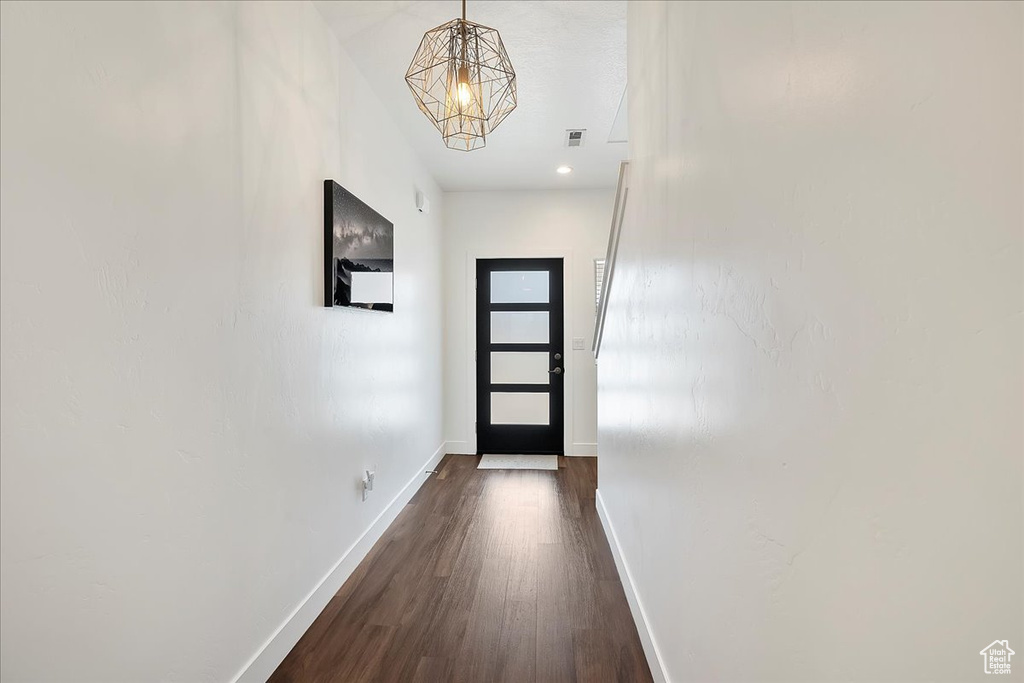 Entryway with dark wood-type flooring and a chandelier