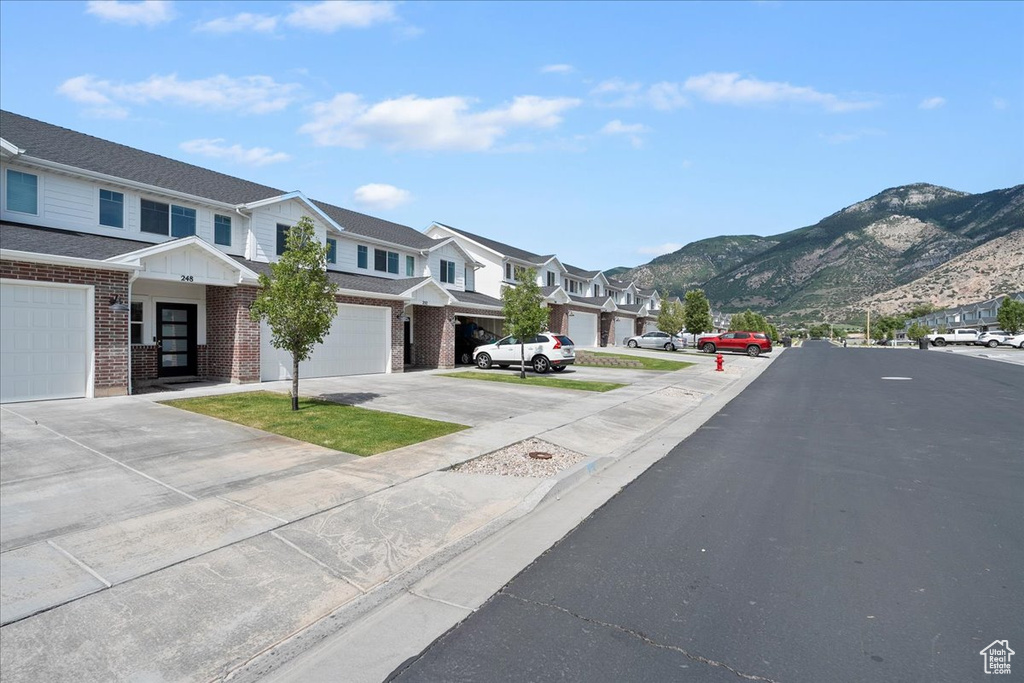 View of asphalt street featuring a residential view, a mountain view, and curbs