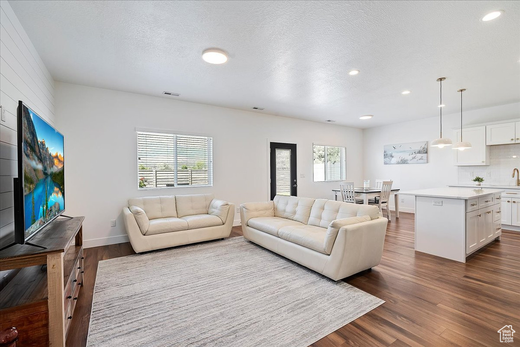 Living room with dark wood-style flooring, recessed lighting, and a textured ceiling