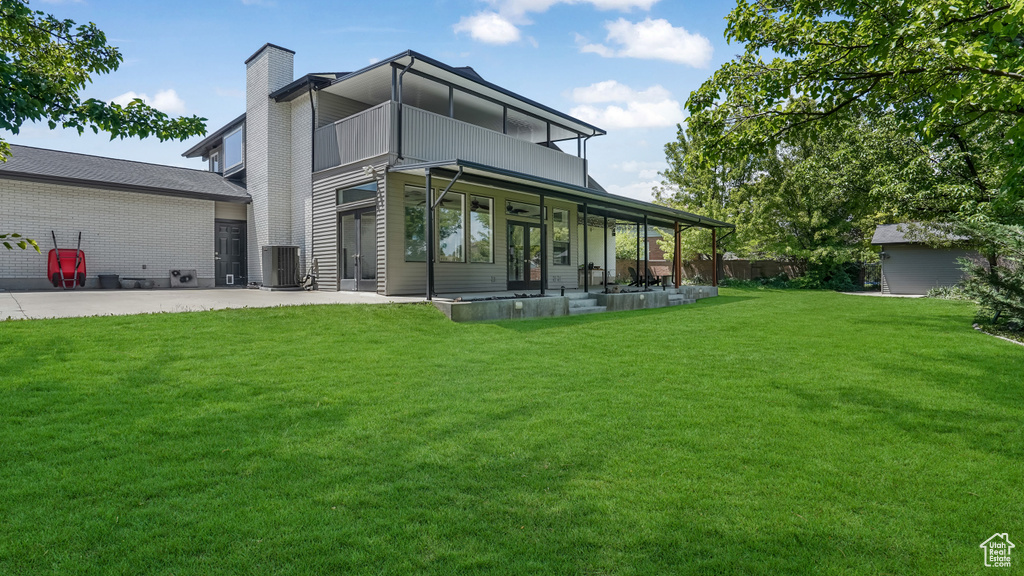 Back of house featuring a patio area, a chimney, a balcony, and french doors
