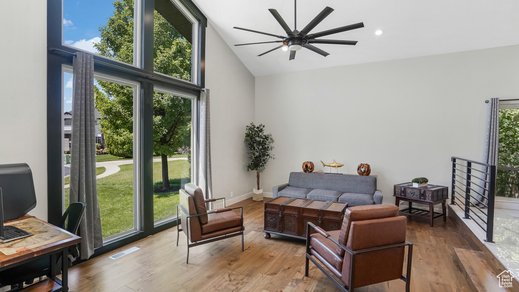 Living room featuring a ceiling fan, high vaulted ceiling, and wood finished floors