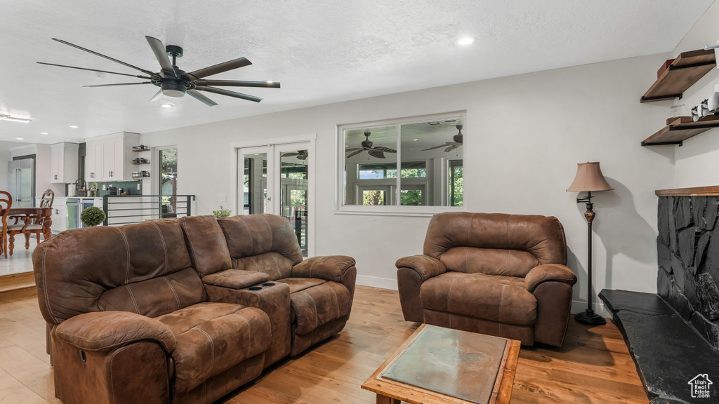 Living room with a ceiling fan, light wood finished floors, and recessed lighting