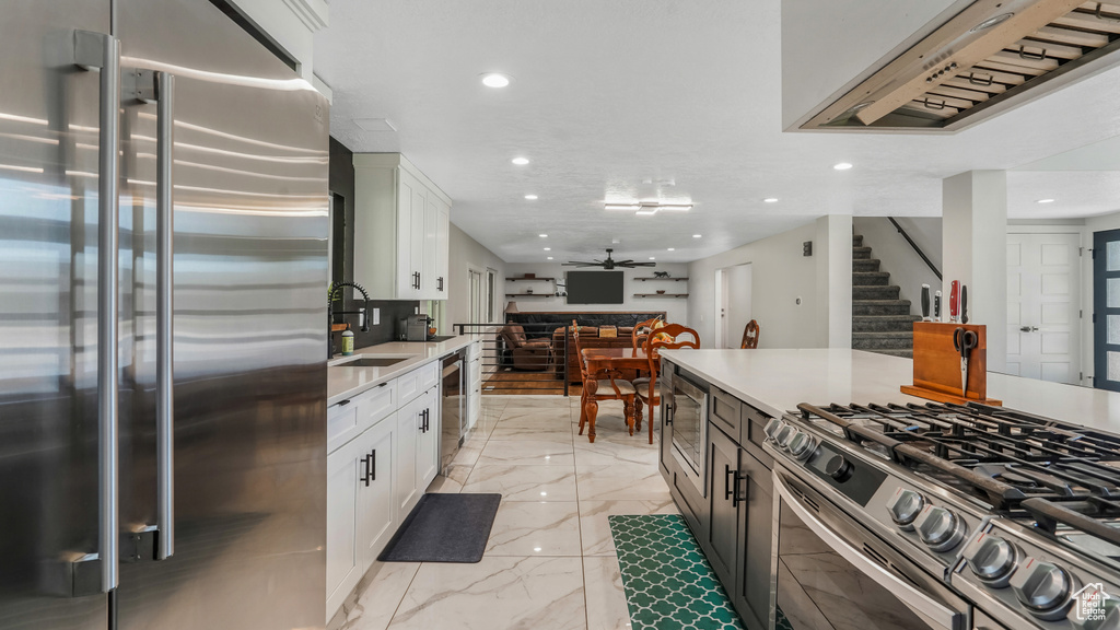 Kitchen with appliances with stainless steel finishes, light marble finish flooring, recessed lighting, white cabinets, and light countertops