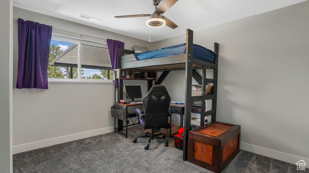 Carpeted bedroom featuring an office area and ceiling fan