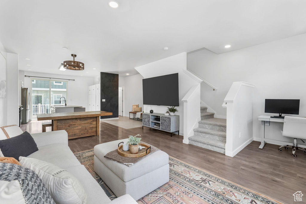 Living room with stairway, wood finished floors, a desk, and recessed lighting